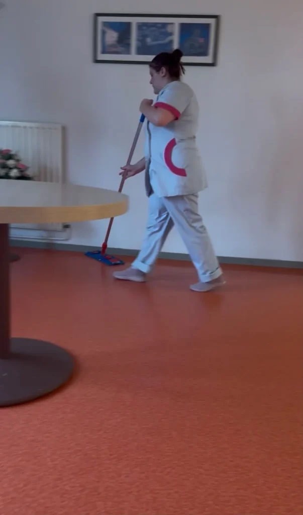 Agente d'entretien nettoyant le sol d'une salle commune