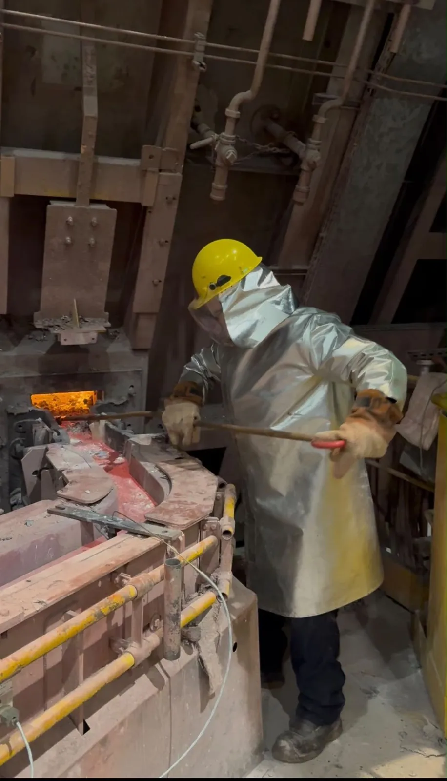 Opérateur en tenue de protection thermique intervenant sur un four de fonderie