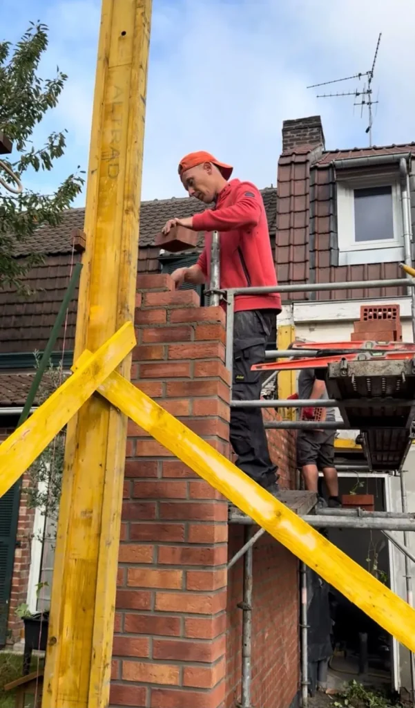 Maçon montant un mur de briques depuis un échafaudage