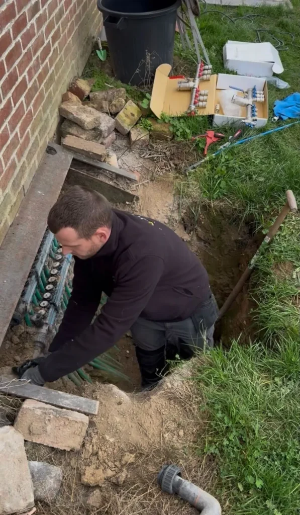 Plombier travaillant dans une tranchée au pied d'une façade